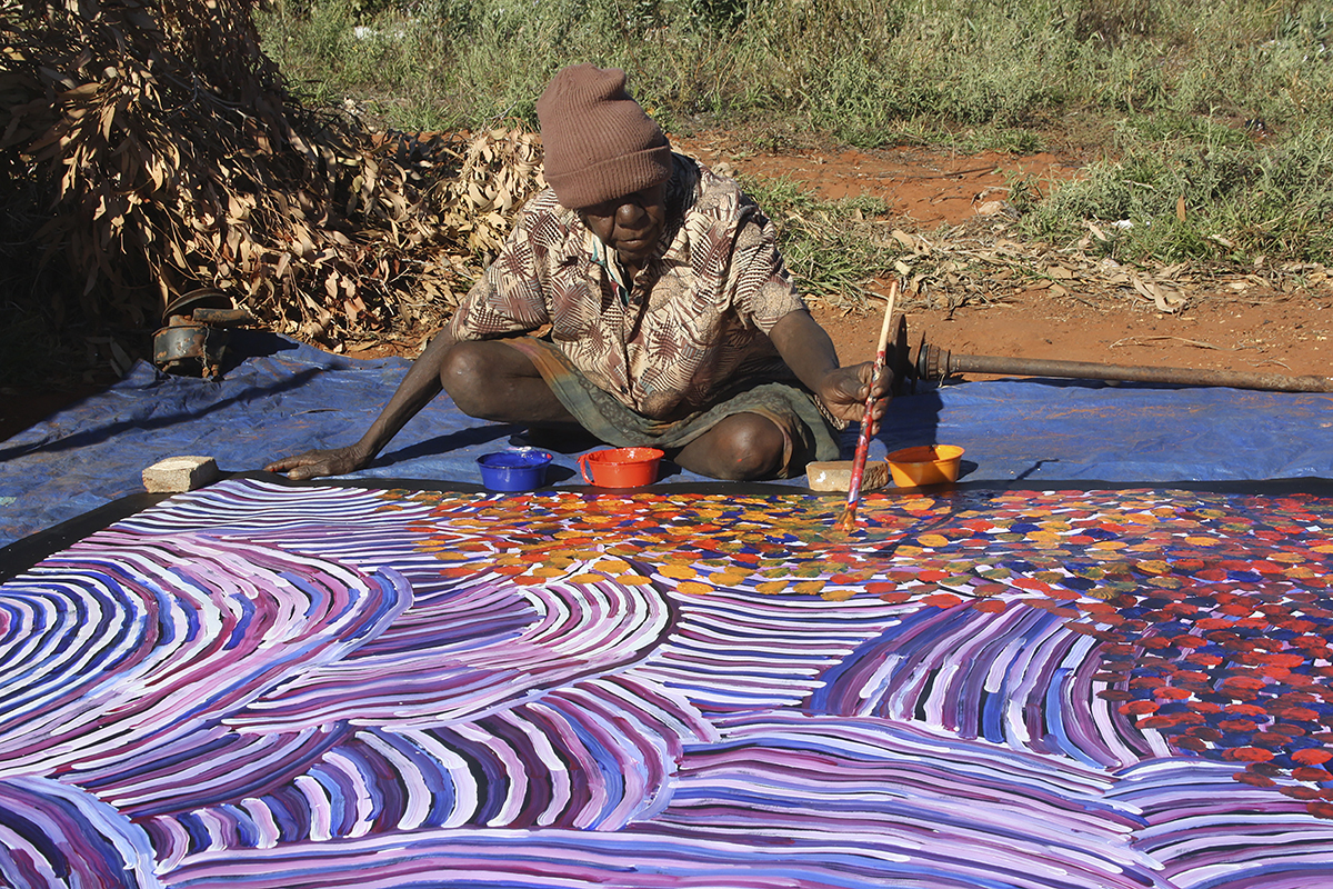 Gayla Pwerle painting outside in Utopia