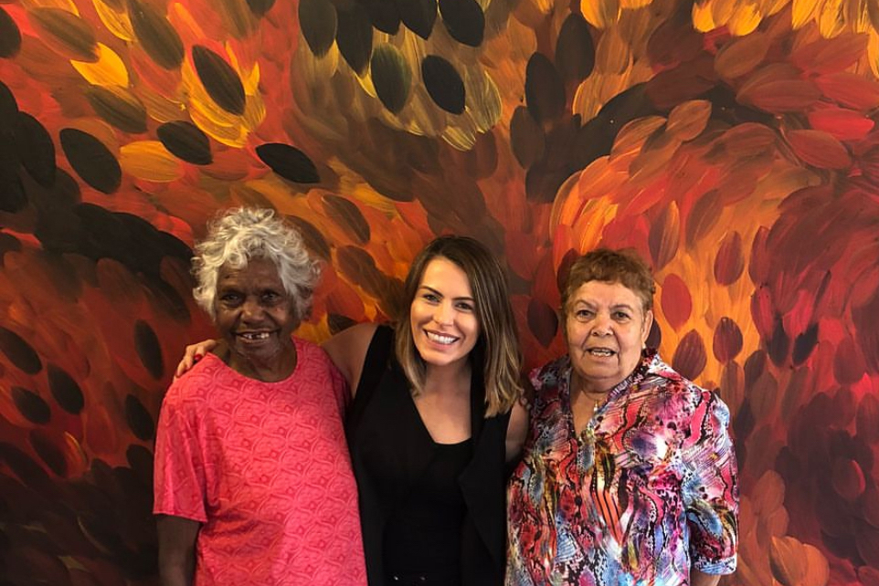 Gloria Petyarre and Barbara Weir at Kate Owen Gallery, standing in front of a large artwork with gallery staff